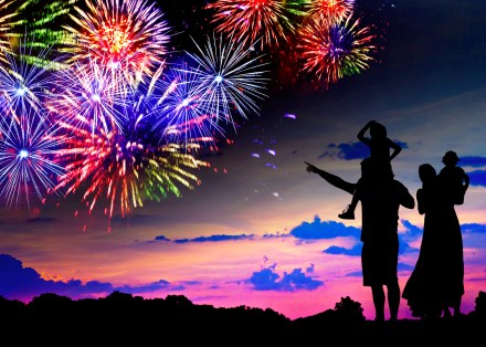 Parents with two children watching fireworks at sunset